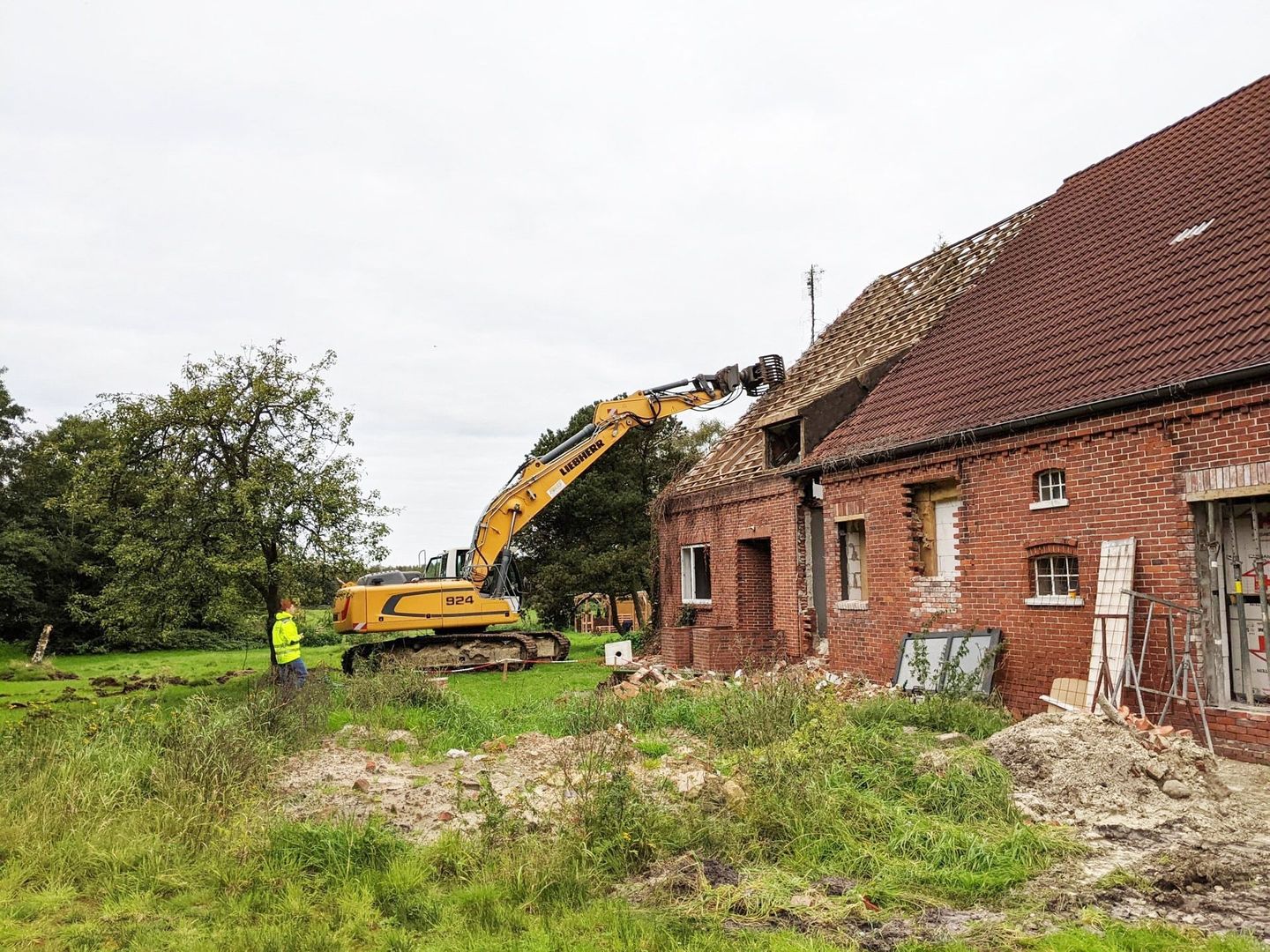 Bagger mit Sortiergreifer beim Teilabriss eines Bauernhauses