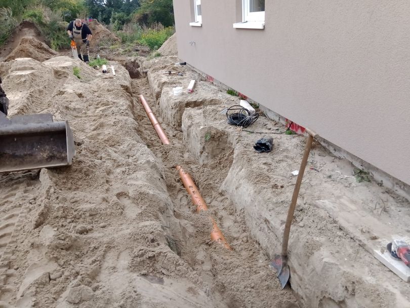 Graben für Kanalarbeiten mit Rohren und Werkzeug.